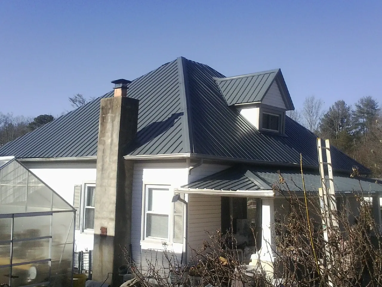 Dark blue standing seam metal roof on a white farmhouse with dormer — Slate & Tile Roof Repair by Roofing Brothers in Sausalito