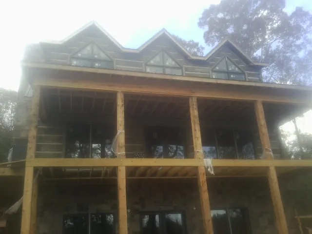 Dormers and porch framing on a large log home under construction — Roof Coating work by our crew in Sausalito